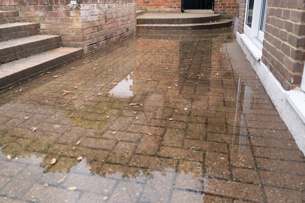 brick patio area flooded after heavy rain due to a blocked soakaway