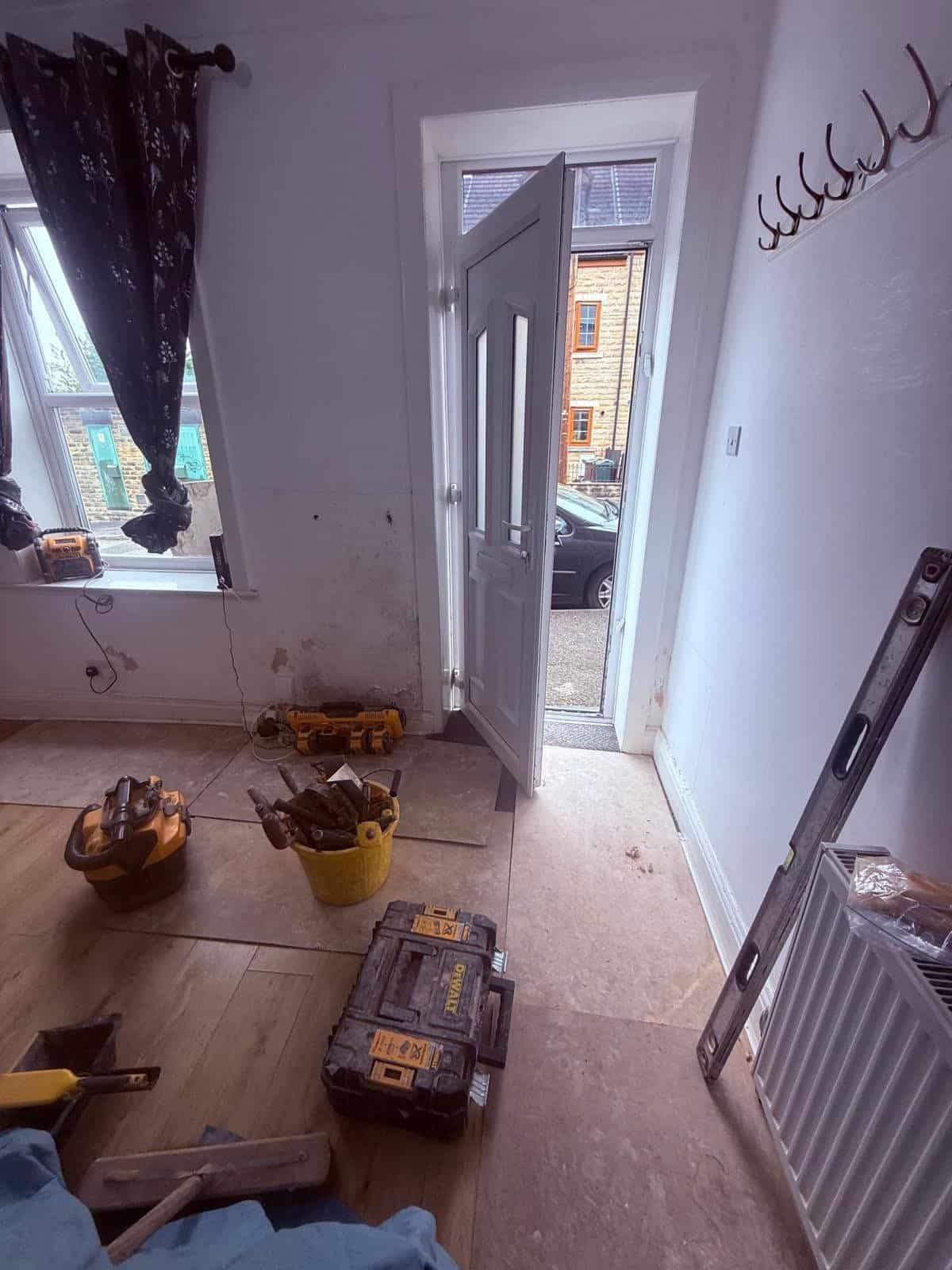 Entrance hallway and front door area of a Barnsley terrace during damp remedial works, with plaster removed at low level