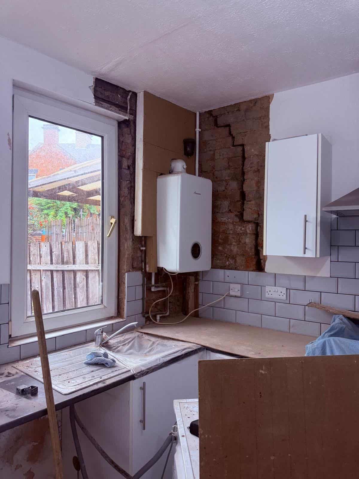 Kitchen in a tenanted Barnsley property part way through damp remedial works, with the chimney breast wall opened up