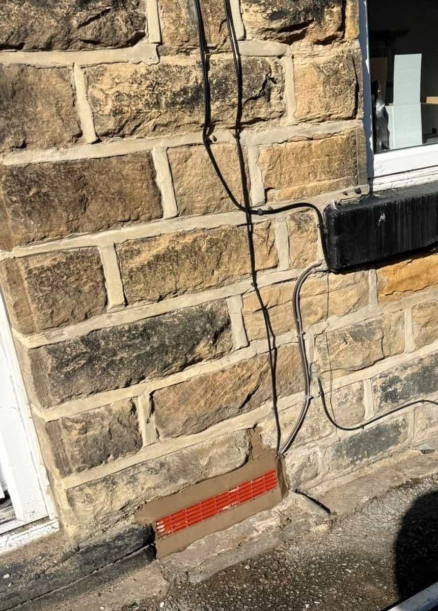 Newly installed terracotta air vent mortared into the stone front elevation of a Barnsley terrace