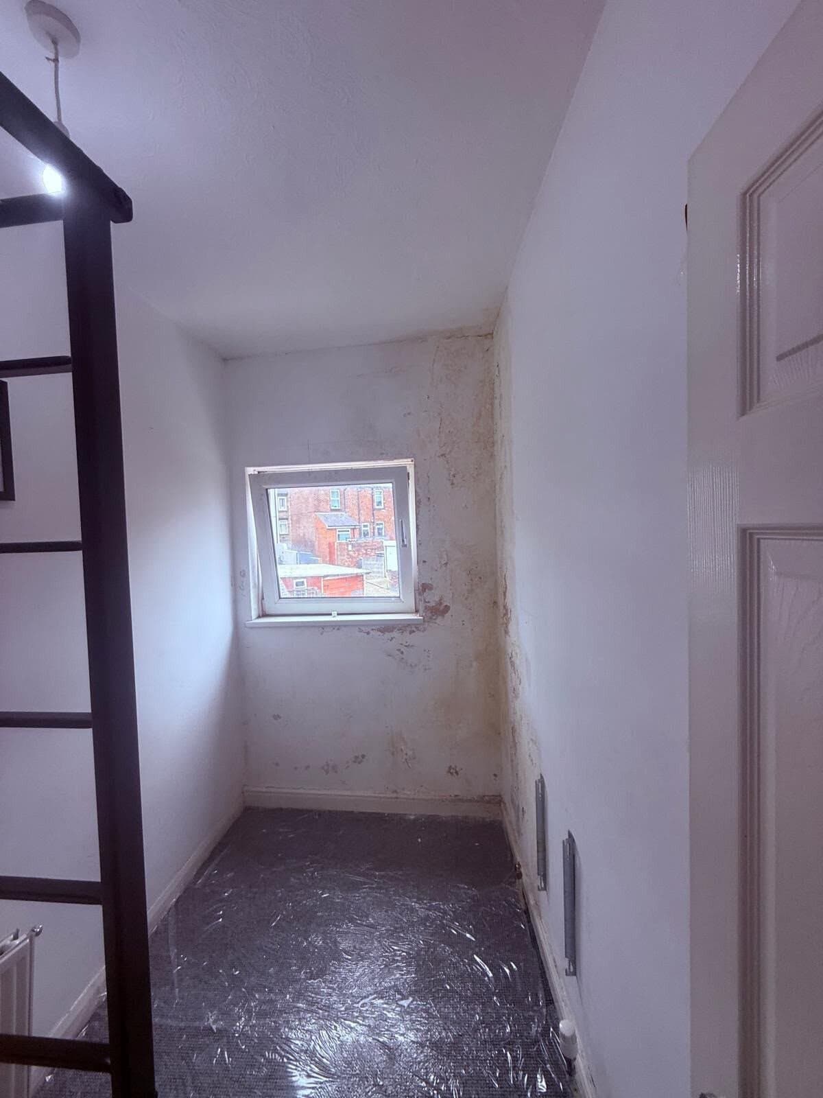 Damp and salt staining around the window of a small rear bedroom in a Barnsley terrace before treatment