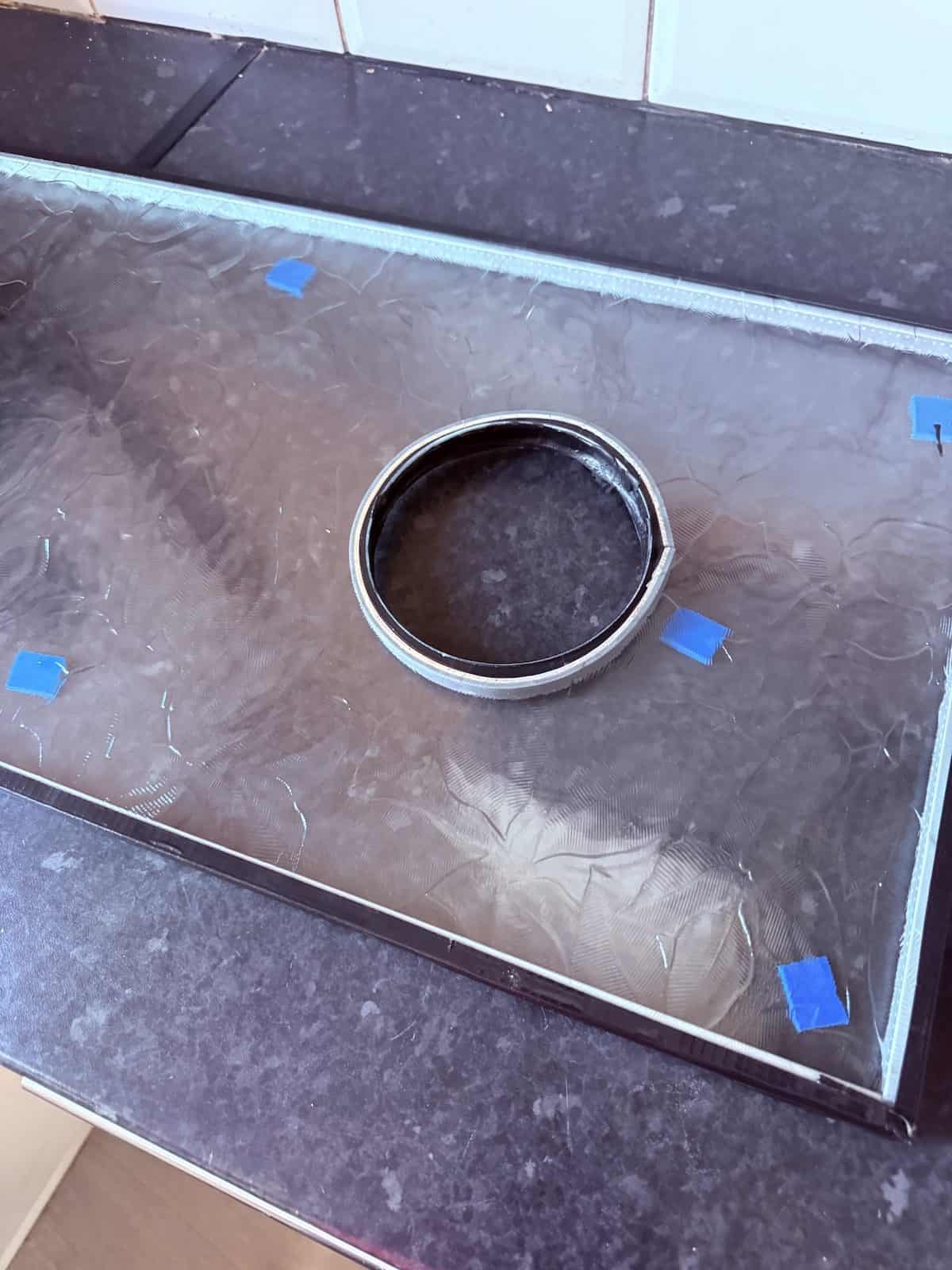 Toughened obscure glass pane on a worktop with a circular aperture cut for an Elta window kit