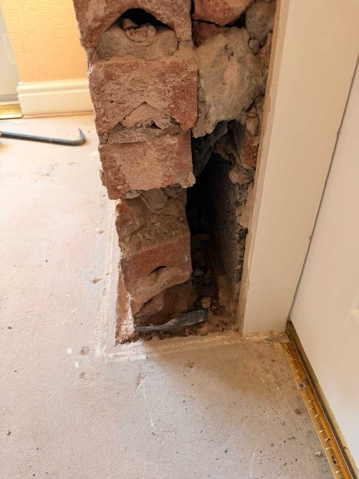 The same cavity at the door reveal after the debris was dug out, with the black damp proof course visible at the base