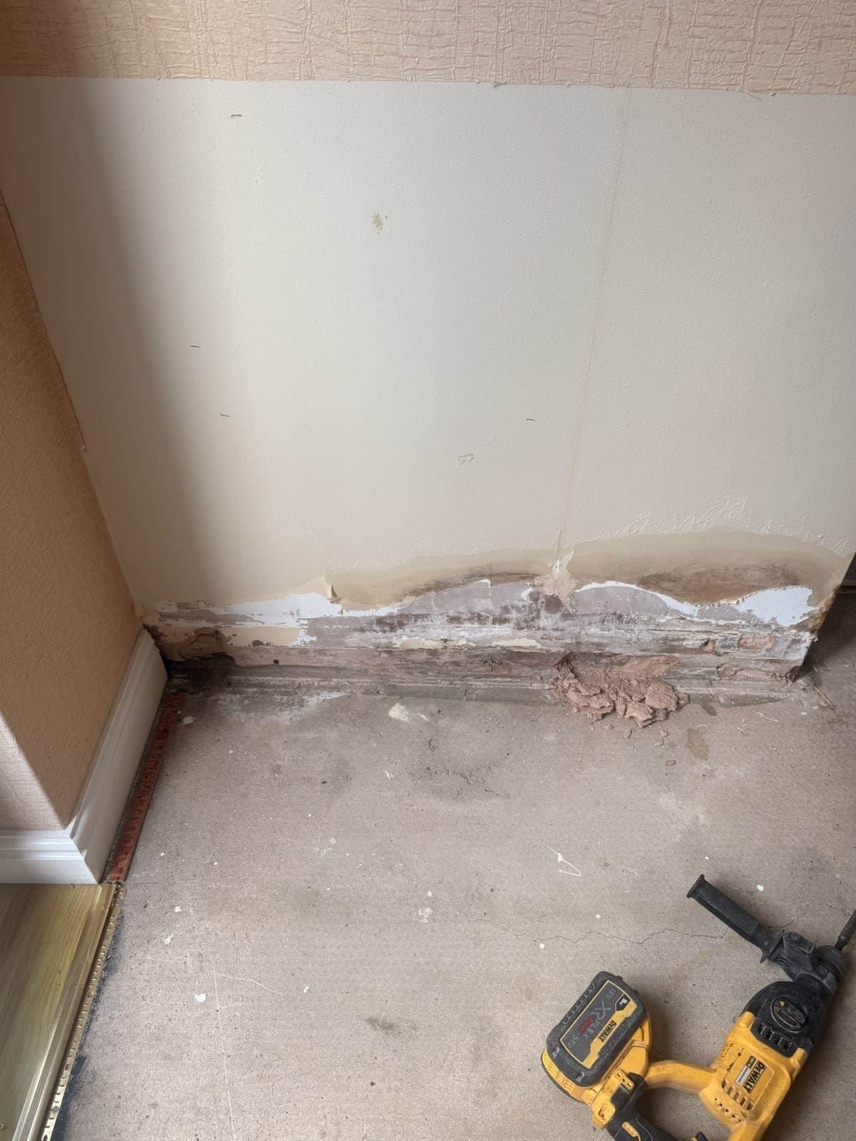Damp stained plaster being removed at skirting level on an extension wall in Royston, Barnsley