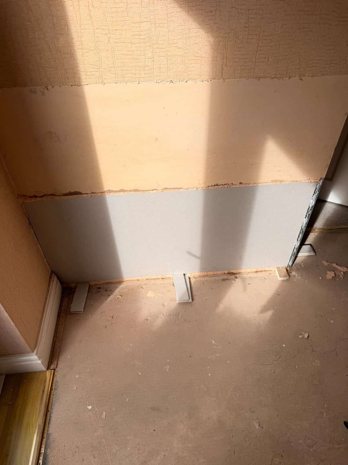 New plasterboard fixed to the lower wall on plastic spacers, leaving a deliberate gap above the solid floor